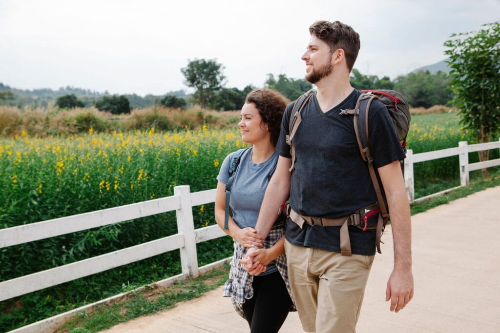 Young couple holding hands and enjoying a walk through a peaceful countryside setting on a sunny day.